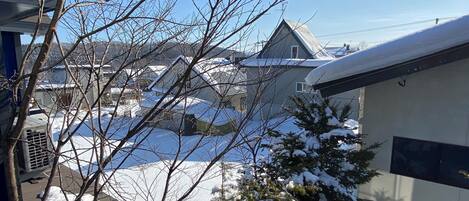 A residential area with houses, a snow-covered roof, and bare trees.