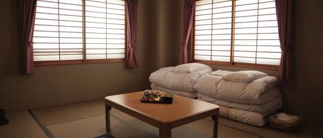 A traditional Japanese room with tatami flooring, a low wooden table, and a futon bed.