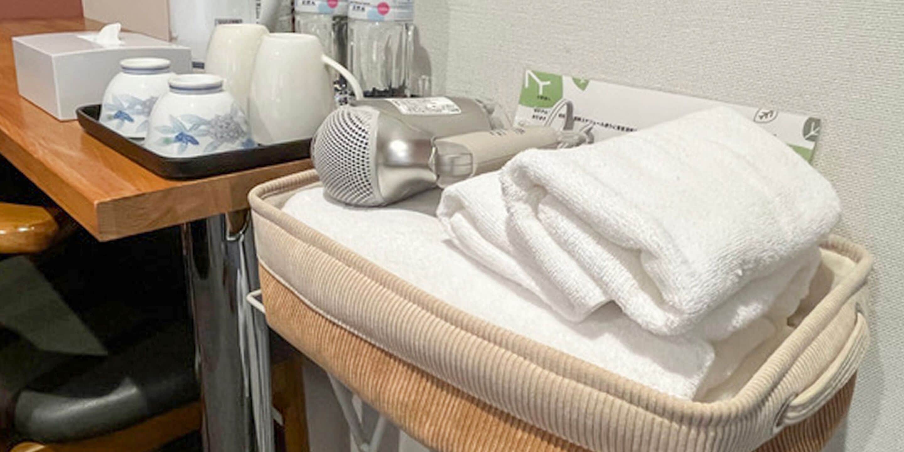 Ein Badezimmer mit Handtuchhalter, einer Korb mit Handtüchern und Pflegeartikeln auf einem Tablett.