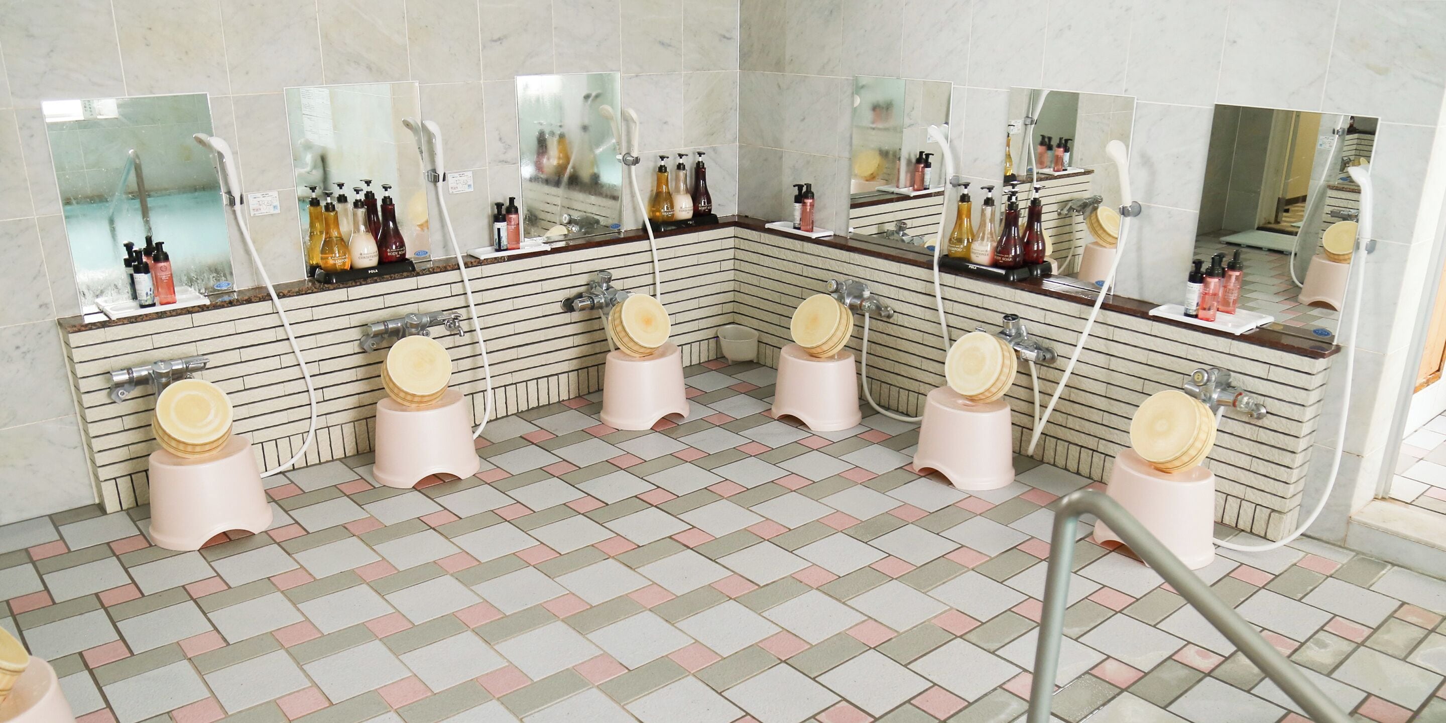 Un baño público con varios lavamanos, espejos y dispensadores de papel higiénico.