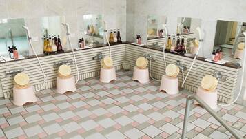 Un baño público con varios lavamanos, espejos y dispensadores de papel higiénico.