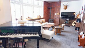 Un salon avec un piano, une cheminée, un téléviseur et une tête de cerf accrochée au mur.