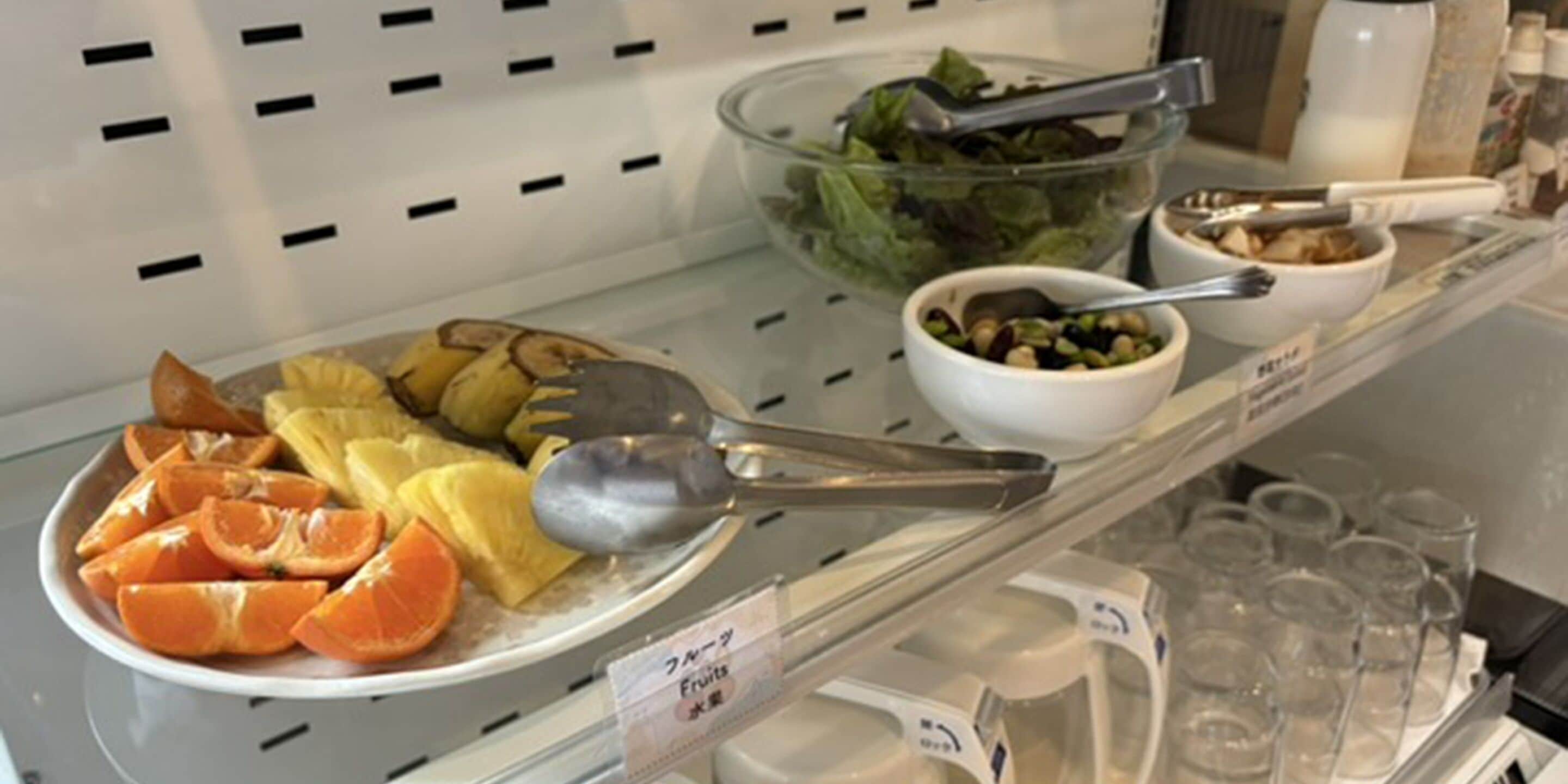 A breakfast buffet with fruits, a salad, and bowls of nuts and seeds.