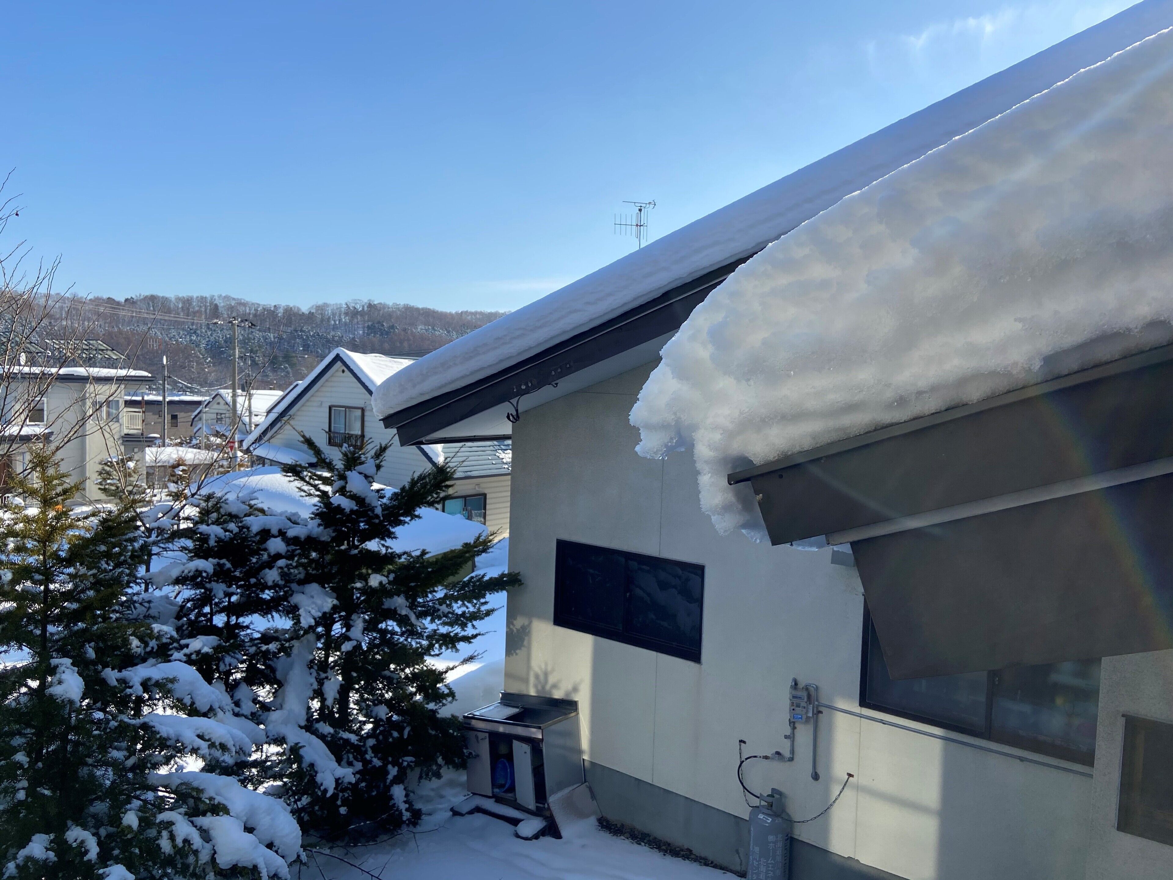 A residential building with snow-covered roofs and a small attached garage.