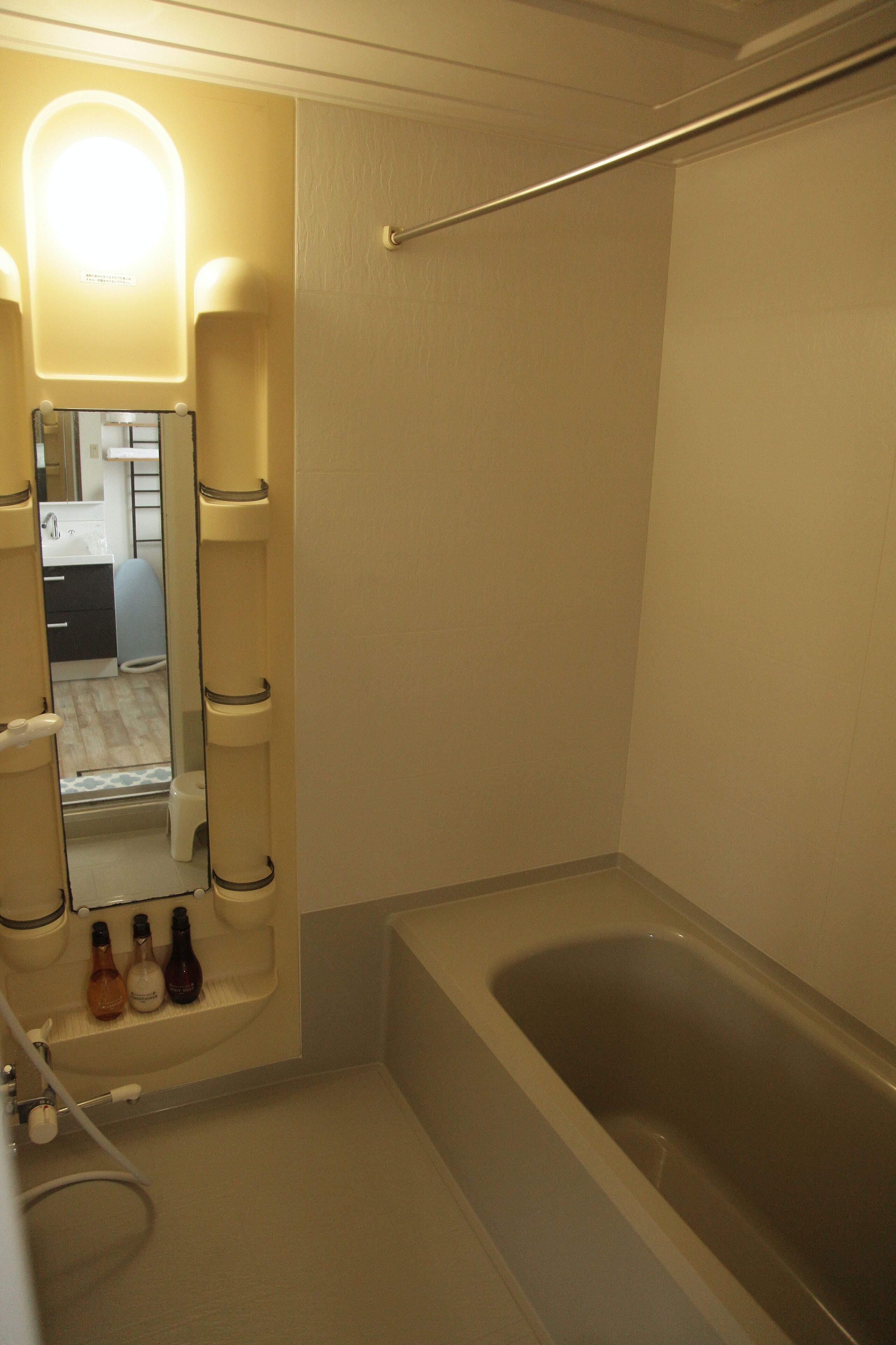 A bathroom with a bathtub, a mirror, and toiletries.