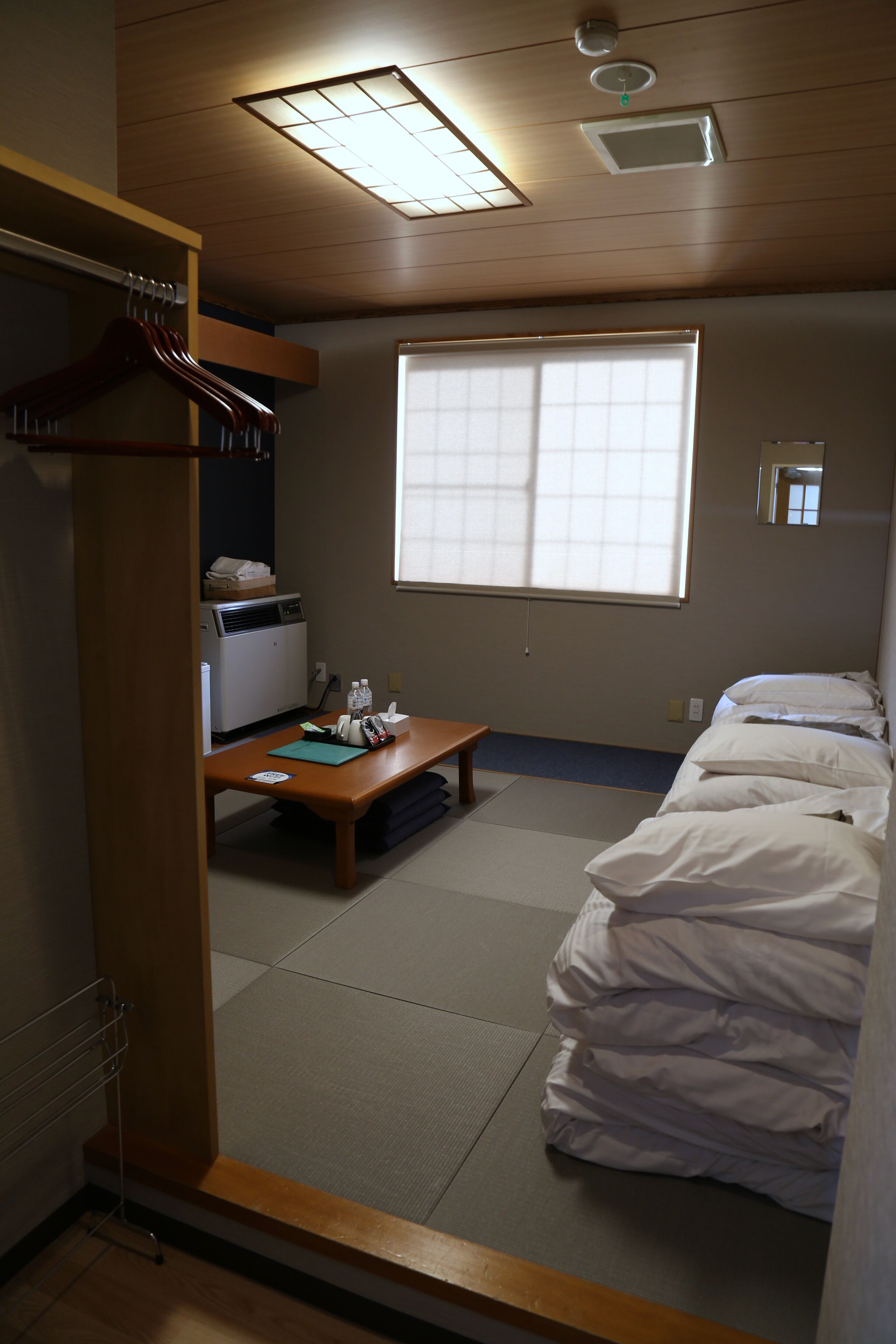 A small, neatly arranged room with a bed, a desk, and a window.