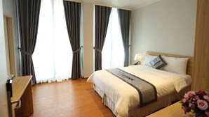 A hotel room with a large bed, a wooden desk, and a nightstand. - Korinn Pho Yen Hotel (Van Xuan)