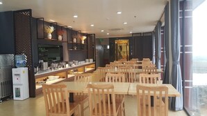 A restaurant with wooden tables and chairs, a counter with a water dispenser, and shelves with decorative items. - Korinn Pho Yen Hotel (Van Xuan)