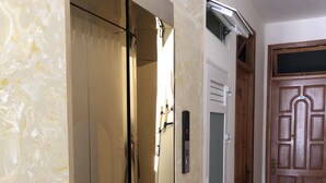 A hallway with a mirrored closet, a wooden door, and a wall-mounted air conditioning unit. - Van Minh Hotel (Xuan Huong - Da Lat)