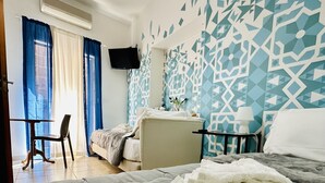A hotel room with a bed, a desk, a chair, and a TV mounted on the wall. - B&B Casa Lilla (Monreale)