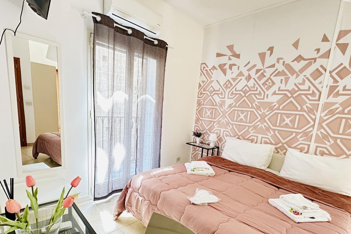 Habitación de hotel con cama, escritorio con silla, televisor y decoración en la pared.
