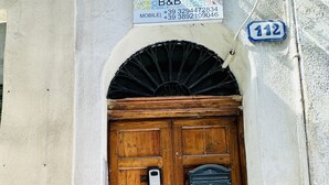 A wooden double door with a sign above it reading "CASA LILLA B&B" and a number "112" on the wall to the right. - B&B Casa Lilla (Monreale)