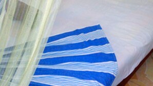 Una cama con ropa de cama blanca y una manta azul a rayas.