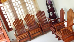Una habitación con sillas de madera dispuestas en fila, una ventana con cortinas y un reloj sujeto a la pared.