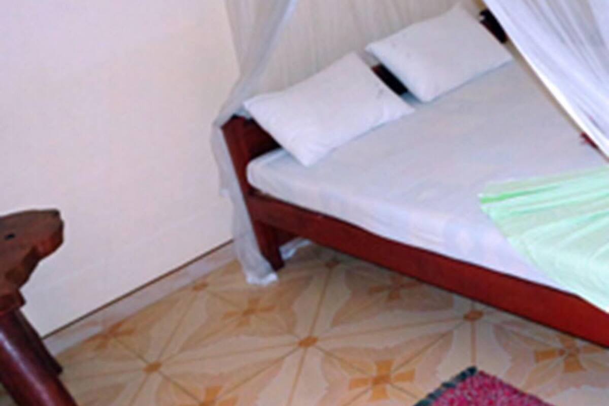 A bed with a canopy, a wooden nightstand, and a patterned floor.