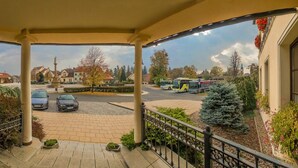 Un espace extérieur abrité offrant une vue sur un parking, une statue et les bâtiments environnants.