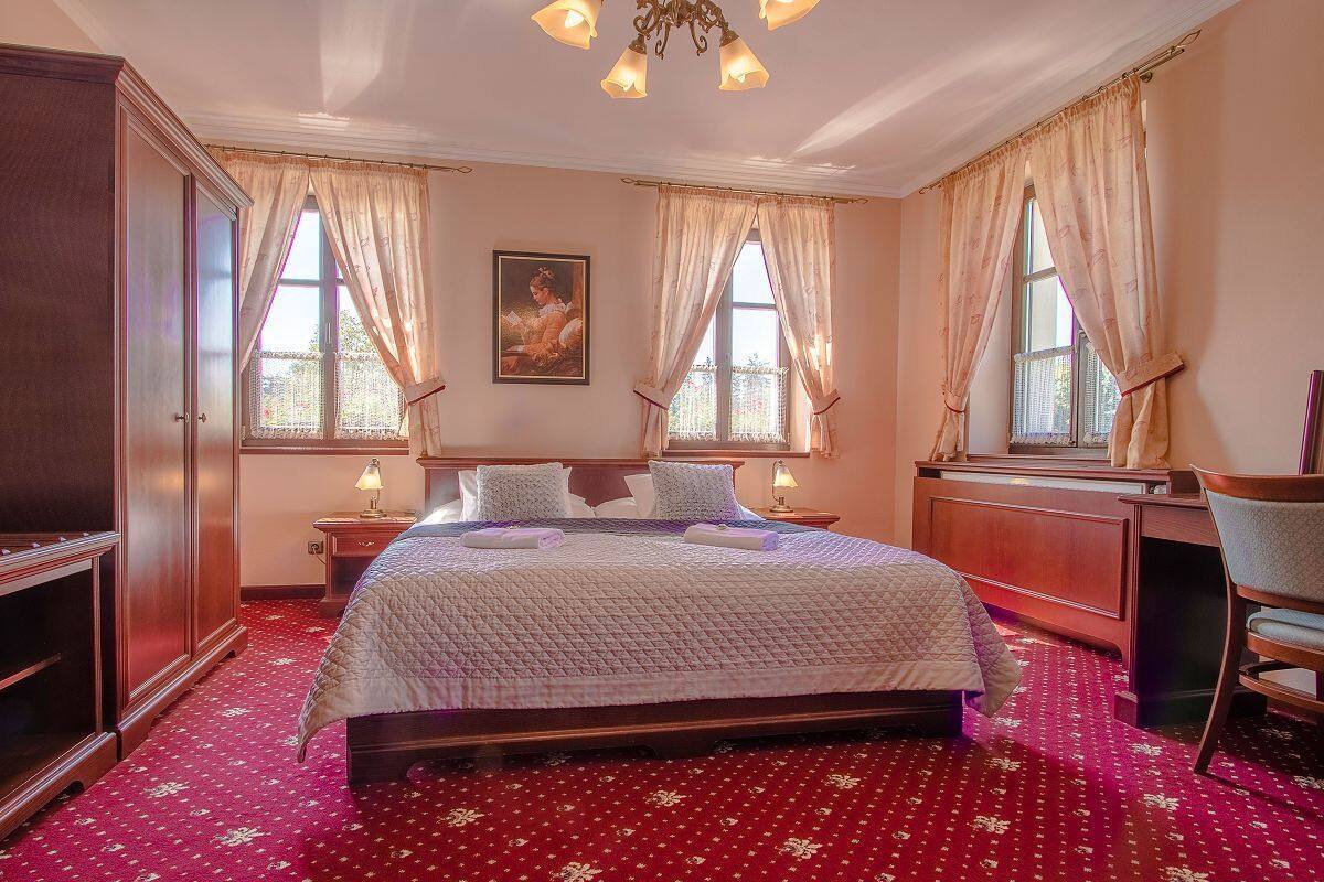 A hotel room with a large bed, two bedside tables, a desk, and a chair.