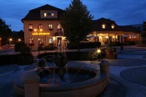 A hotel with a fountain in the courtyard, a well-maintained garden, and a building with multiple windows and lights. - Hotel Buchlovice (Buchlovice)