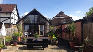 A courtyard with a wooden bench, potted plants, and a table. - Random Hall Hotel (Horsham)