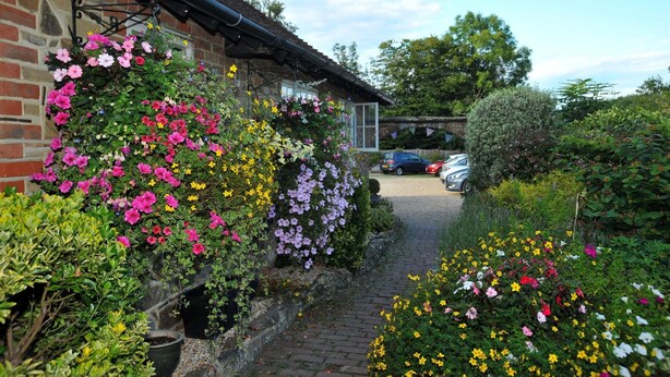 A brick building with a garden path leading to a car parked in the background. - Random Hall Hotel (Horsham)