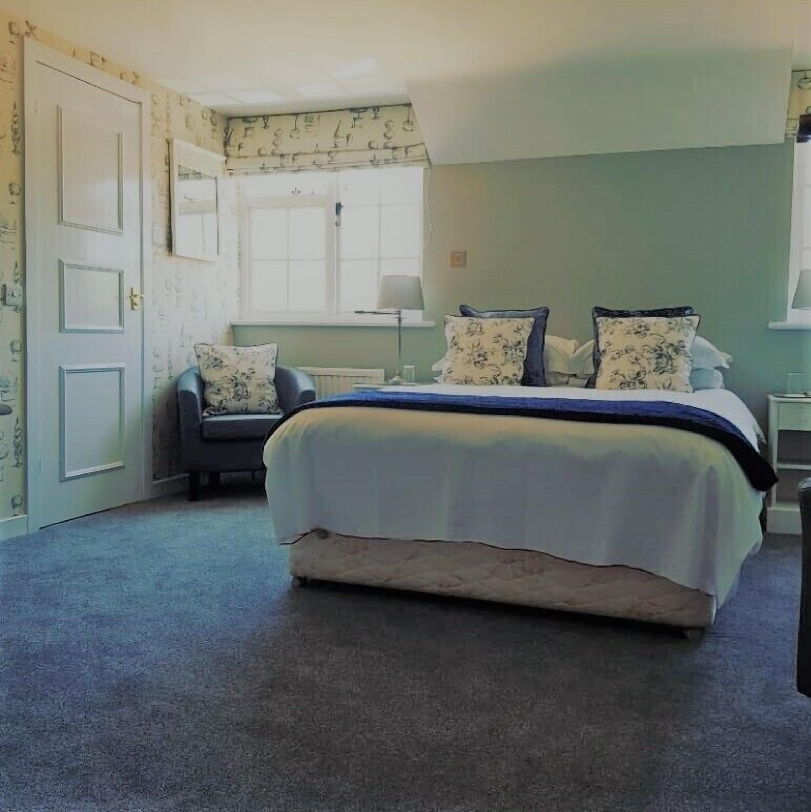 A bedroom with a bed, a chair, and a desk.