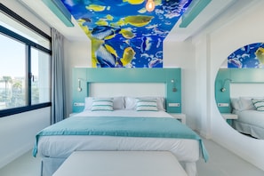 A modern bedroom with a large bed, a ceiling mural of fish, and a view of palm trees outside. - HD Acuario Lifestyle (Las Palmas de Gran Canaria)