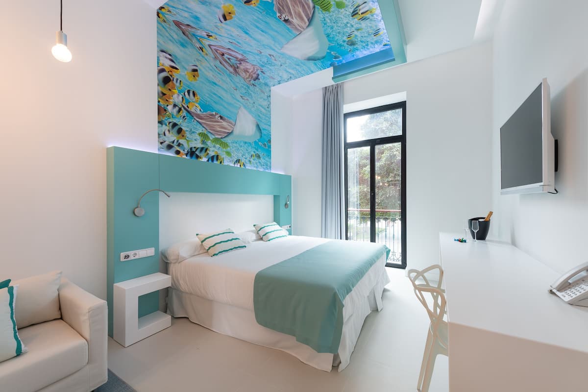 A modern bedroom with a large bed, a desk, and a TV.