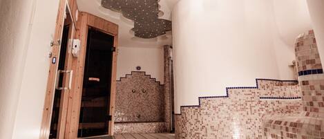A hallway with a wooden door, tiled floor, and a wall with mosaic tiles.