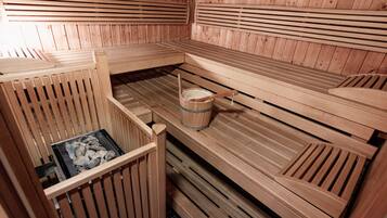 Eine Sauna mit Holzbänken und einem Eimer Steine.