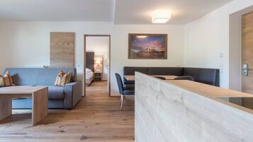 Una moderna camera d'hotel con parquet, un divano, un tavolo da pranzo e un quadro appeso al muro.