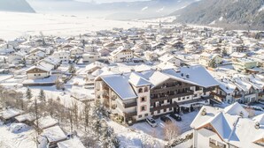 Un pueblo cubierto de nieve con edificios tradicionales y un hotel destacado con varios pisos y balcones.