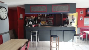 Una zona de bar con un reloj, taburetes y un área de estar con mesas y sillas.