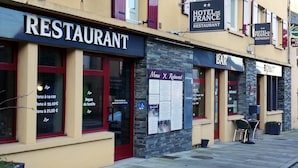 Un restaurante con fachada de piedra, ventana de marco rojo y cartel de menú en el exterior.