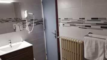 A bathroom with a white sink, a mirror, a towel rack, and a shower with a handheld showerhead.