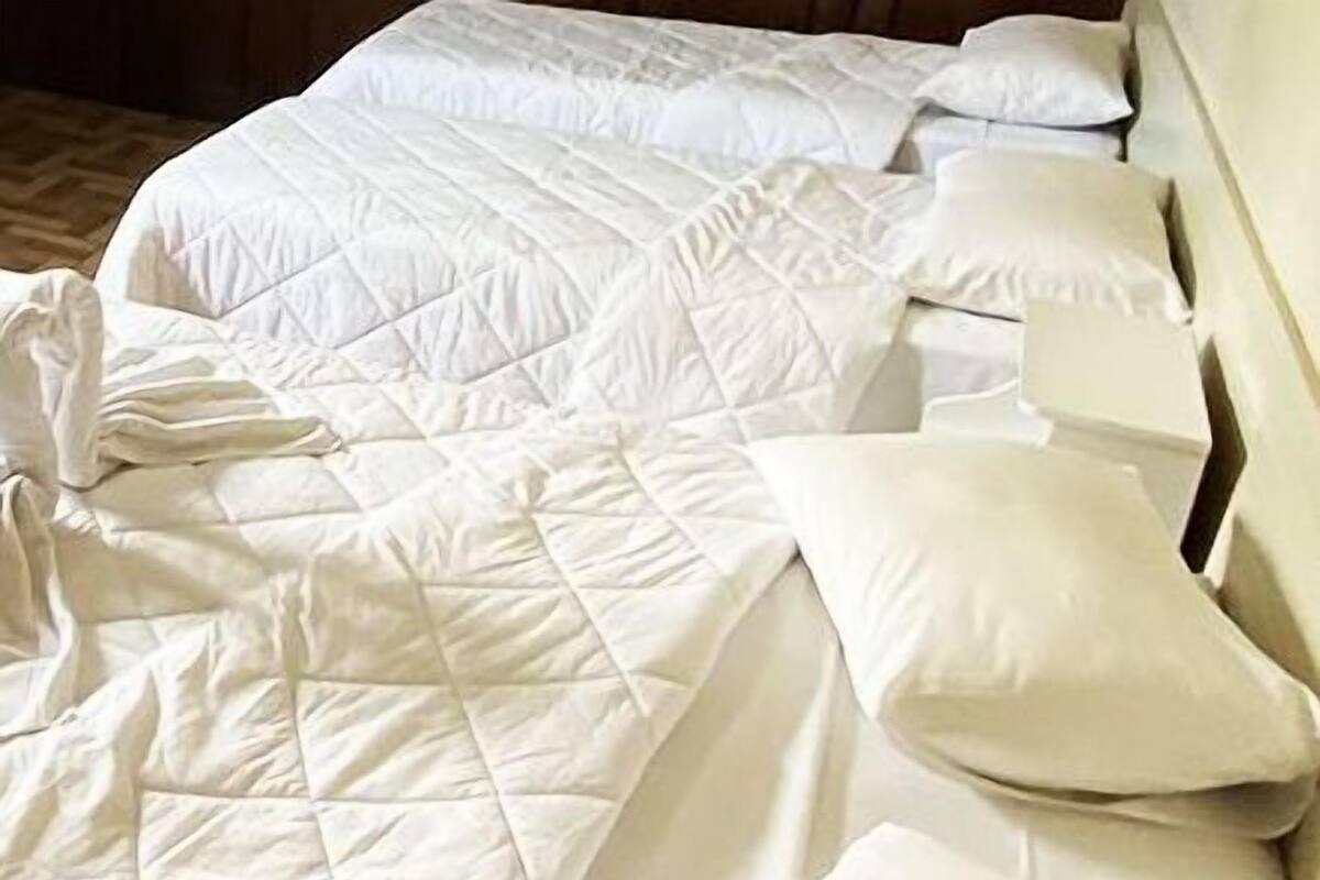 Ein ordentlich bezogenes Bett mit einer gesteppten weißen Decke und mehreren Kissen.