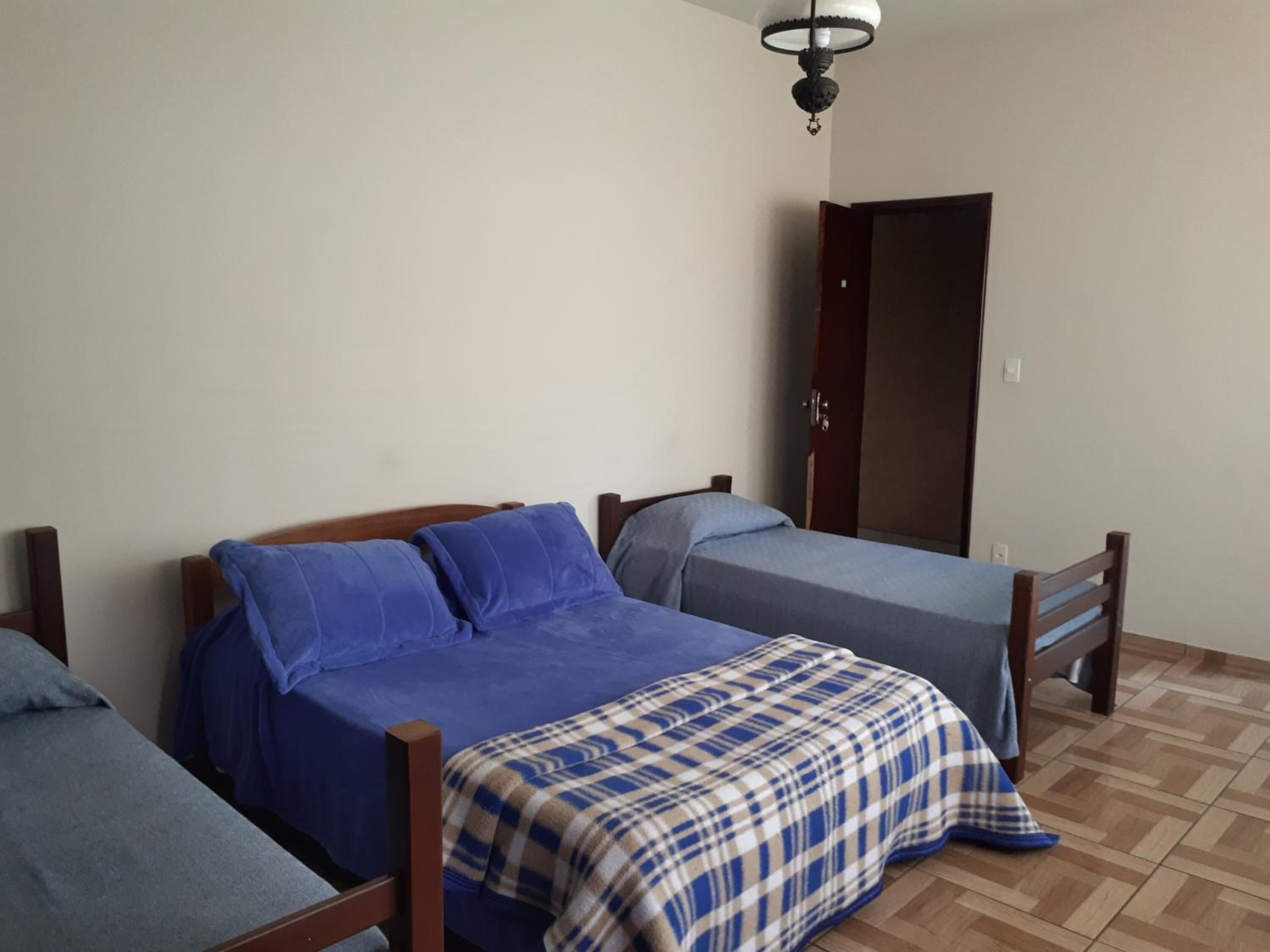 Ein Zimmer mit zwei Betten, jedes mit anderer Bettwäsche. Es gibt eine Holztür und eine Deckenleuchte.