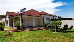 A house with a covered patio, a small garden, and a solar panel on the roof.