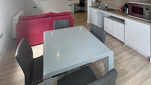Un espacio habitable moderno con comedor, kitchenette y un sofá rojo.