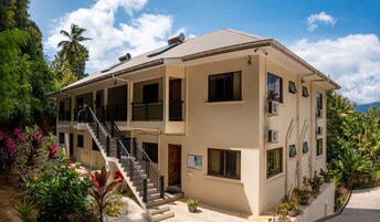 Un edificio de dos pisos con escaleras, varias ventanas y unidades de aire acondicionado.