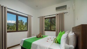 Ein Hotelzimmer mit einem Bett, Bettwäsche in Grün und Weiß, einem Telefon und einem Fenster mit Vorhängen.