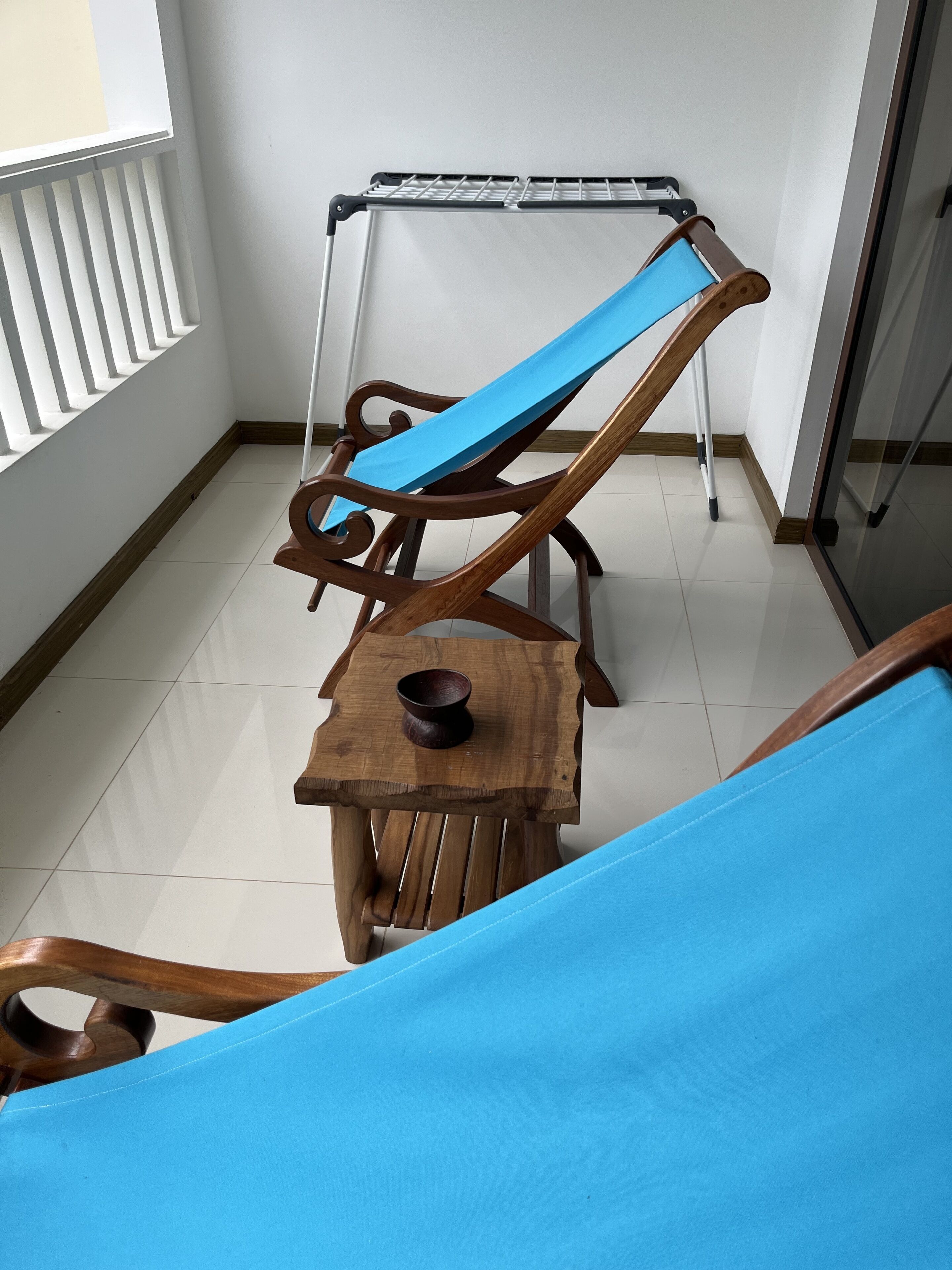 A wooden chair with a blue cushion and a small wooden table with a bowl.