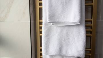 Ein Badezimmer mit einem goldenen Handtuchhalter und drei weißen Handtüchern.