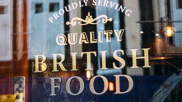 Uma janela com a inscrição 'SERVINDO COM ORGULHO COMIDA BRITÂNICA DE QUALIDADE'.