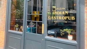 En pub med en skylt som visar texten ”Indisk gastropub” och en annan skylt i fönstret med texten ”Hantverksöl”.