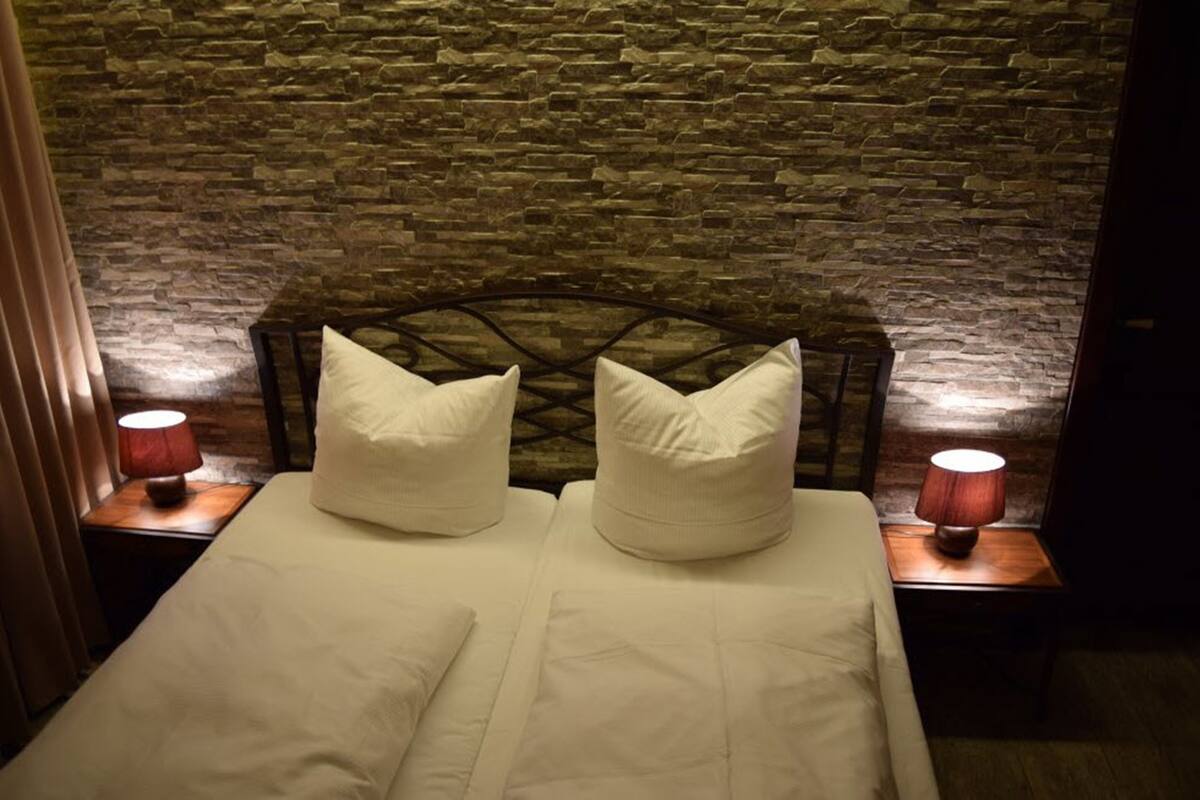 A bed with a headboard, two pillows, and two bedside lamps.