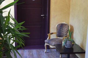 A dark wooden door, a leopard print chair, a small table with a woven basket, and a potted plant.