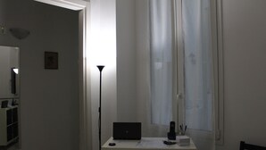 A room with a desk, a laptop, a lamp, and a window with curtains. - Gymnasium (Syracuse)