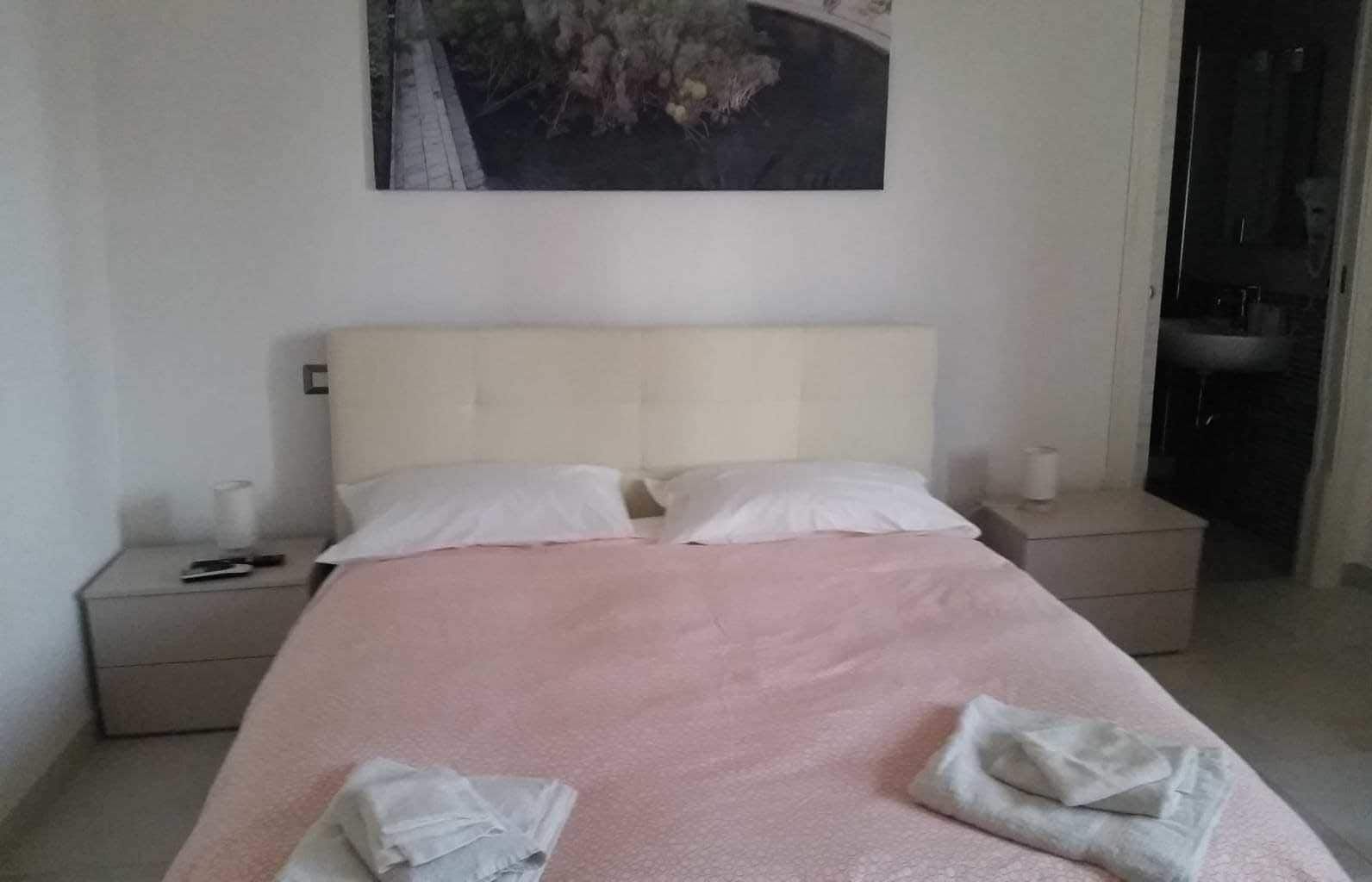 Una camera da letto con un letto, due comodini e un quadro appeso al muro.