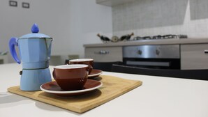 A kitchen with a coffee maker, two cups, and a wooden board. - Gymnasium (Syracuse)