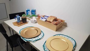 A dining table with two plates, a coffee maker, and a basket of bread. - Gymnasium (Syracuse)